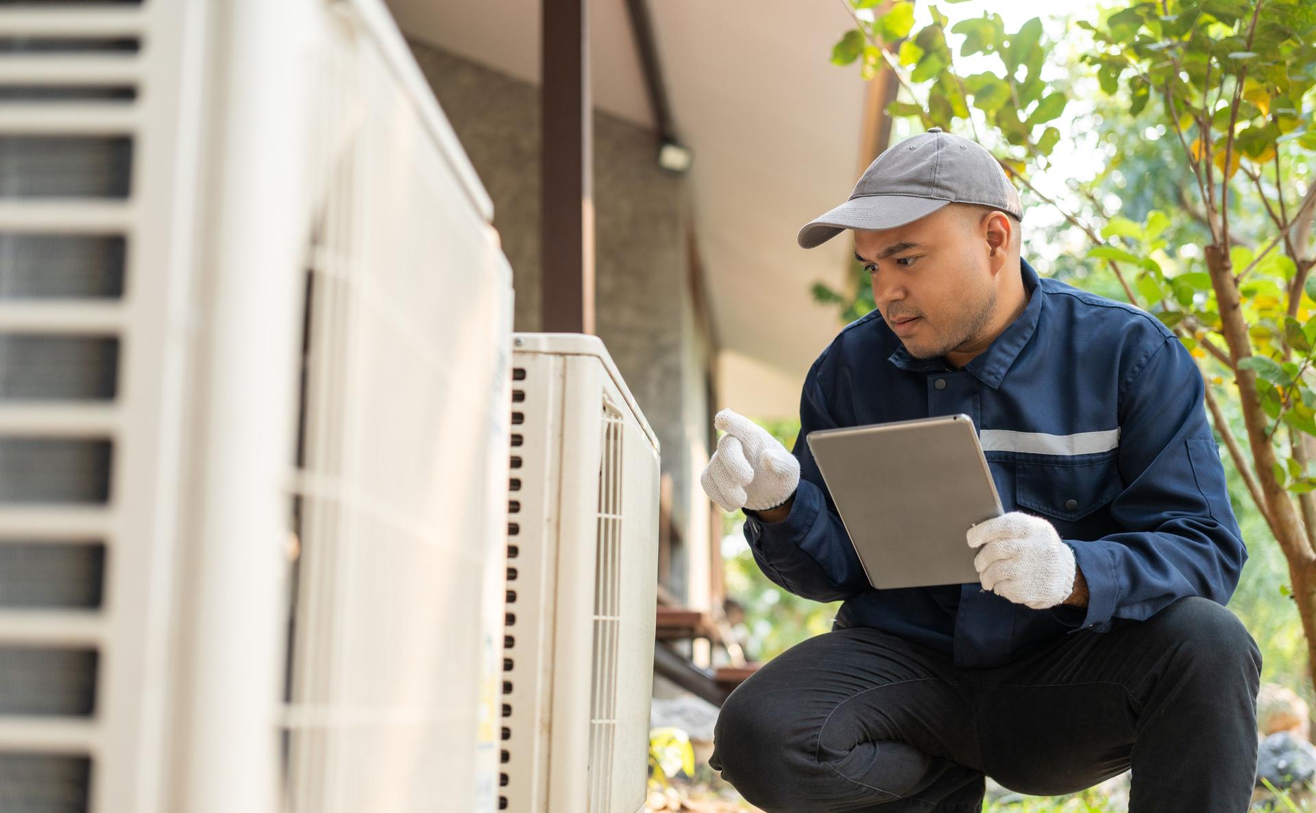 Air conditioner service outdoor checking fix repair. Air conditioner cleaning technician He opened the front cover and took out the filters and washed it. He in uniform wearing rubber